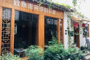 A traditional wooden building with large glass doors and windows, surrounded by greenery. - Tongli Jizhu Inn (Suzhou)