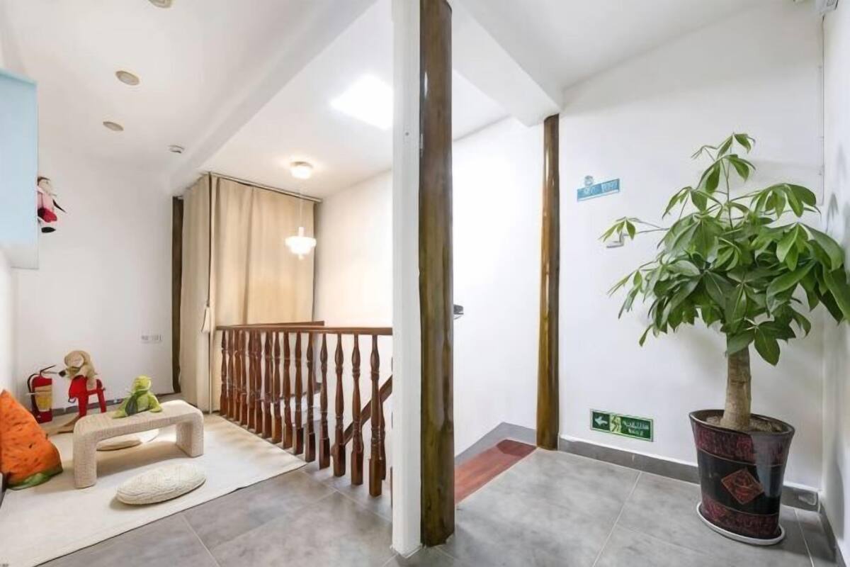 Un pasillo con barandilla de madera, una planta en maceta, un banco y un tapete pequeño.