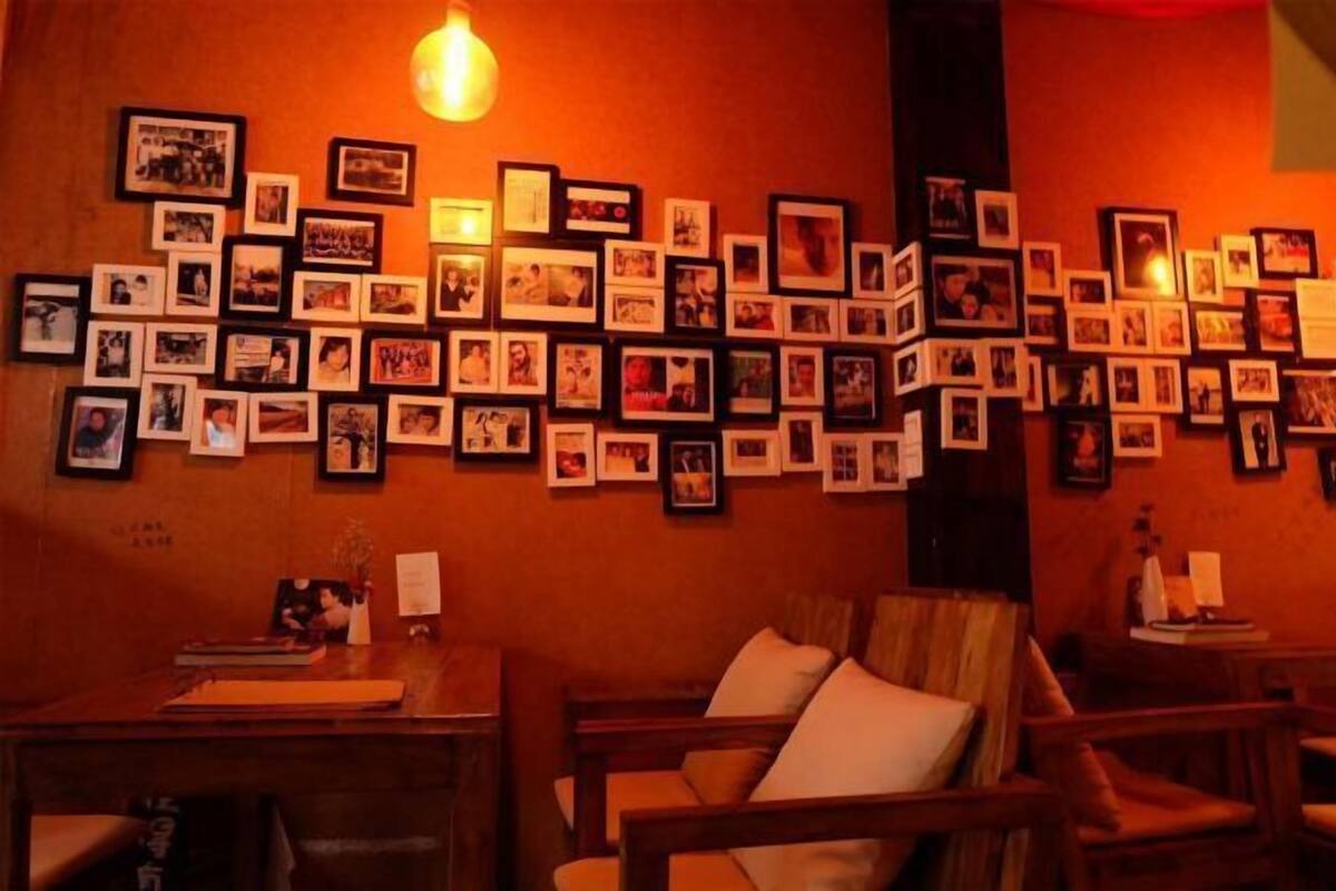 Una habitación con una pared de fotos enmarcadas, un escritorio de madera y una silla acolchada.