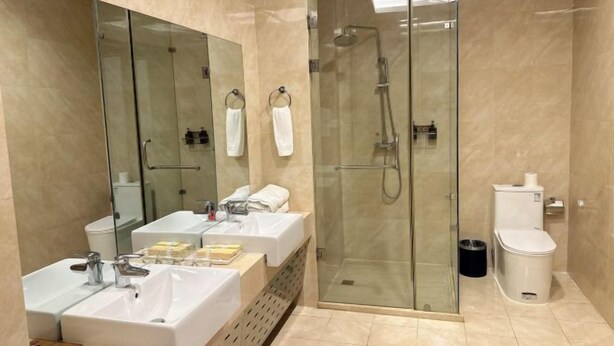 A modern bathroom with a glass-enclosed shower, a double sink vanity, and a toilet.