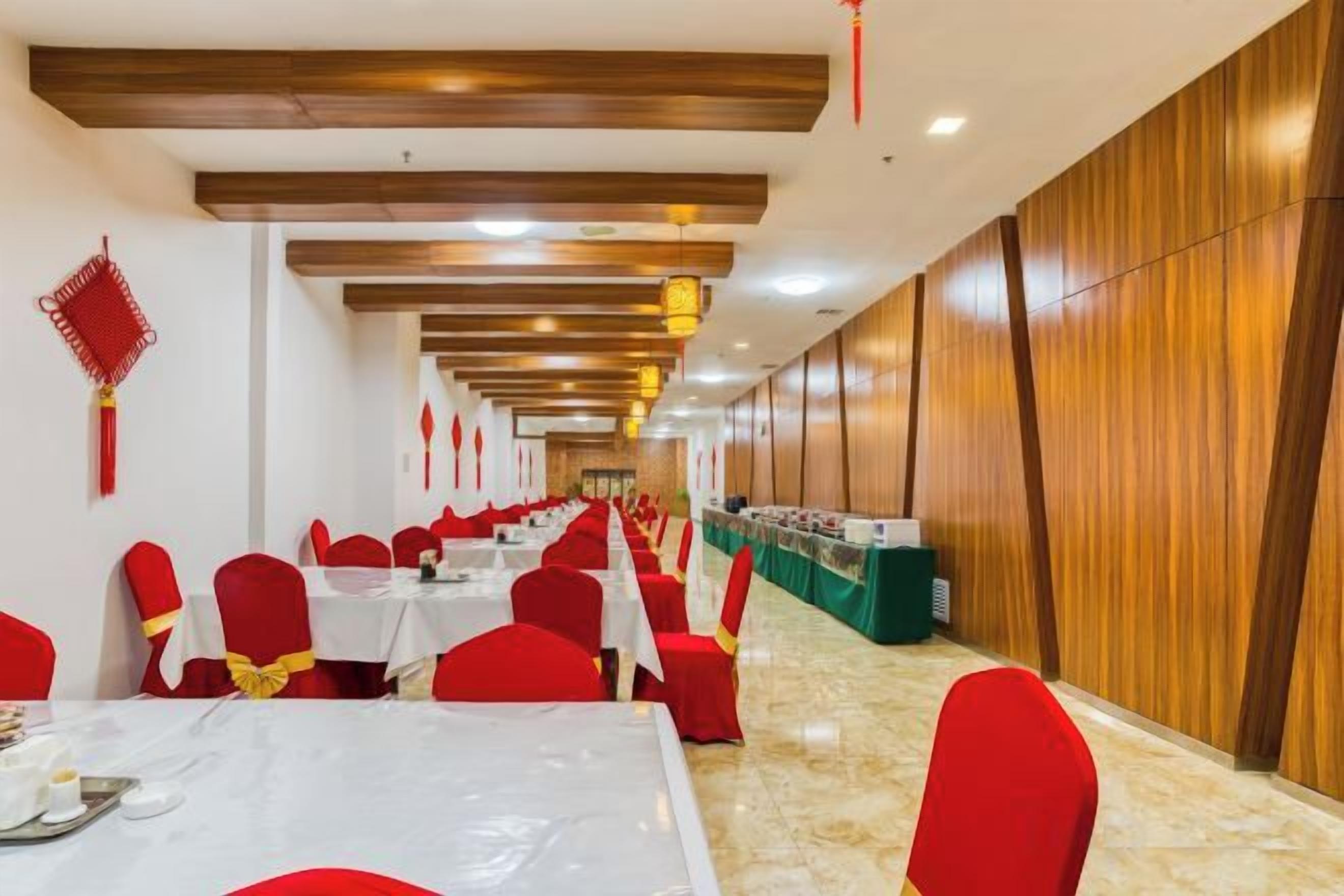 A banquet hall with rows of tables and chairs, wooden paneling on the walls, and a long table with a green tablecloth.