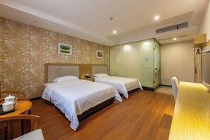 A hotel room with two beds, a wooden floor, a dining table, and a small kitchen area.