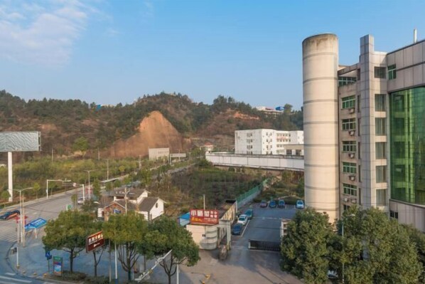 Un edificio moderno con una estructura cilíndrica, un estacionamiento y un fondo con colinas.