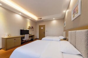 A hotel room with two beds, a desk with a chair, a television, and a door.