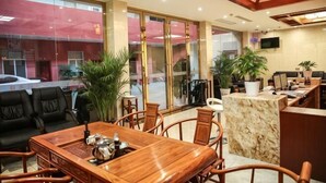 Un vestíbulo de hotel con mostrador de recepción, zona de estar y grandes ventanales.