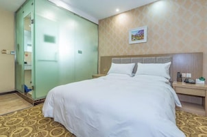 Una habitación de hotel con cama, mesita de noche, escritorio y armario.