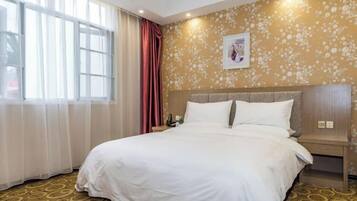 Une chambre d’hôtel avec un grand lit, une table de chevet, une horloge murale et une fenêtre avec des rideaux légers.