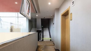 Un pasillo con puerta de madera, escalera y un separador de vidrio.