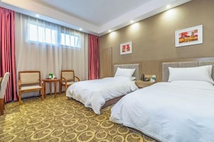 Habitación de hotel con dos camas, un escritorio, sillas y una mesita.