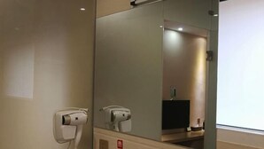 Een hotelkamer met een haardroger en een spiegel.