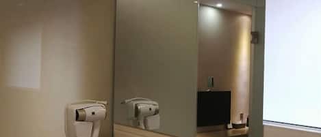 Habitación de hotel con secador de pelo y espejo.