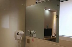 Habitación de hotel con secador de pelo y espejo.