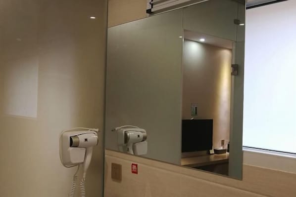 A hotel room with a hairdryer and a mirror. - Tangmen Inn (Enshi)