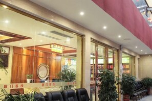 Un vestíbulo de hotel con recepción, zona de estar y plantas en macetas.