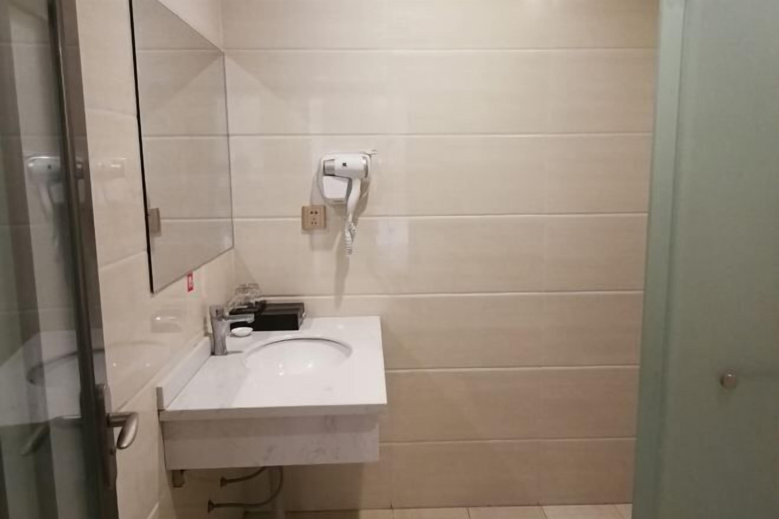 Un bagno con un lavandino bianco, uno specchio e un asciugamani ad aria montato a parete.
