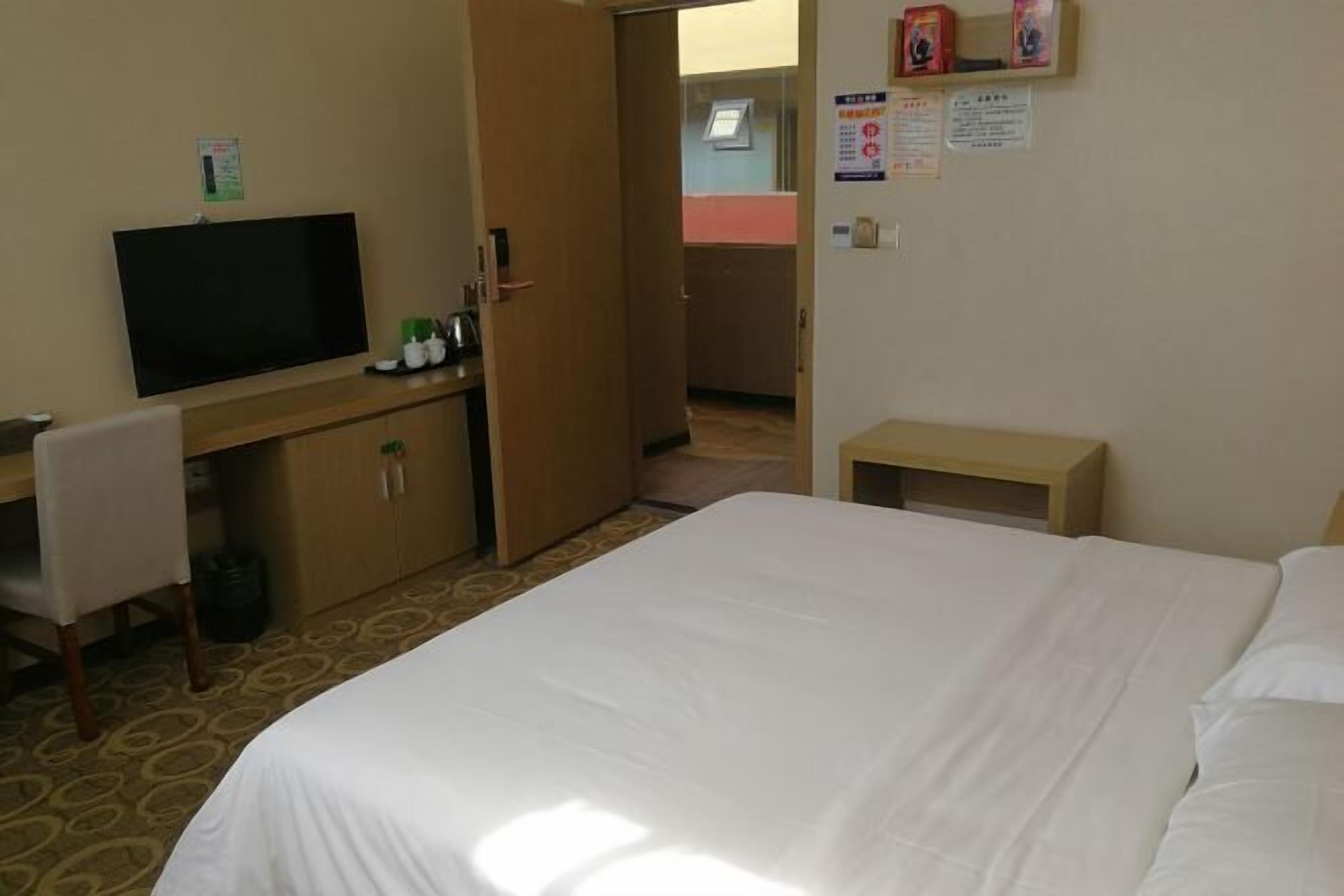 A hotel room with a bed, a desk, a television, and a small table.