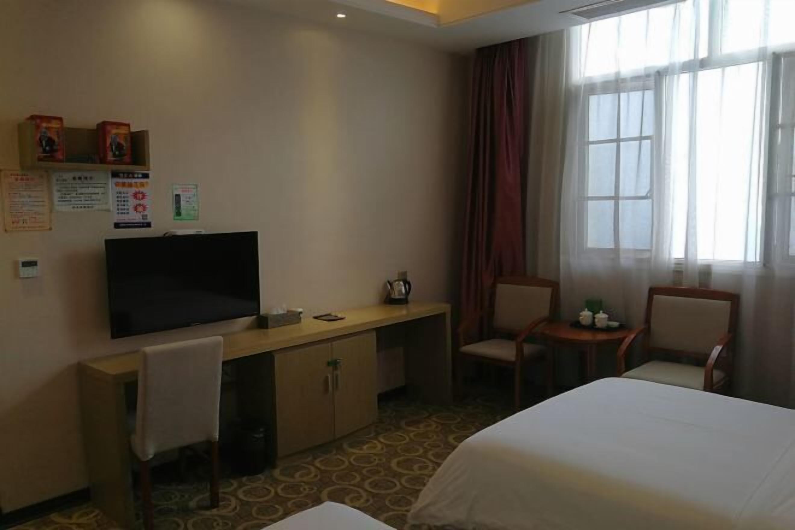 Une chambre d’hôtel comprenant un lit, un bureau avec un téléviseur à écran plat, une chaise et une petite table.