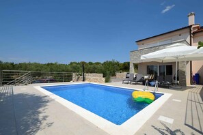 A rectangular swimming pool with a clear blue water, surrounded by a tiled deck. - Holiday home with a pool and three bedrooms (Barušići)