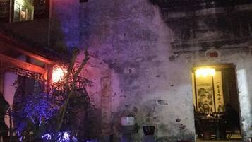 A historic building with traditional architecture, a courtyard with plants, and a well-lit entrance.