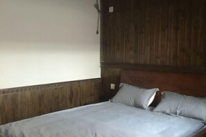 A single bed with a wooden headboard and a grey bedspread. - Bishan Zhoujiayuan Farmhouse (Yi County)