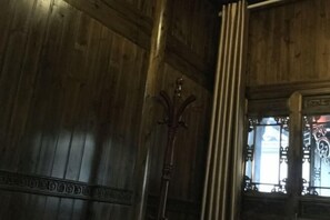 A wooden interior with a decorative coat rack and a window with intricate metalwork. - Bishan Zhoujiayuan Farmhouse (Yi County)