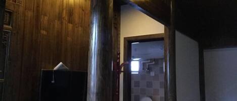 A wooden interior with a television, a toilet, and a door leading to another room.
