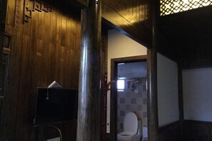 A wooden interior with a television, a toilet, and a door leading to another room. - Bishan Zhoujiayuan Farmhouse (Yi County)