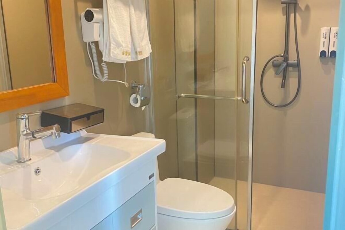 A modern bathroom with a glass-enclosed shower, a white sink, and a toilet.