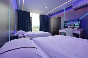 A modern hotel room with two beds, a desk, and a TV.