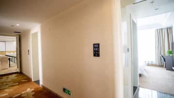 A hotel corridor with a carpeted floor, a sign indicating room 801, and a door leading to a room with a bed and a window.