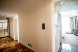 A hotel corridor with a carpeted floor, a sign indicating room 801, and a door leading to a room with a bed and a window.