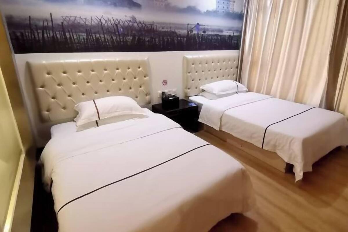 A hotel room with two beds, each with a tufted headboard and white bedding.
