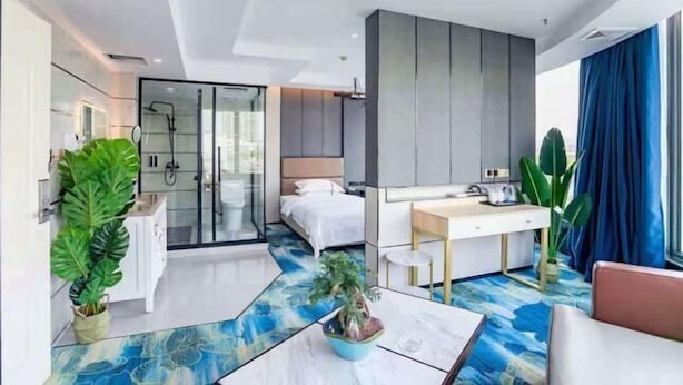 A modern hotel room with a bed, a desk, a shower area, and a large window with curtains. - Yili Hotel (Kaiping)