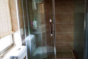 A bathroom with a glass shower enclosure, a toilet, and a window with blinds. - Ninghai Jiumufang (Ninghai)