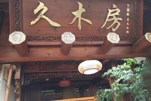 A wooden building facade with large gold Chinese characters, decorative brackets, and a hanging light fixture. - Ninghai Jiumufang (Ninghai)