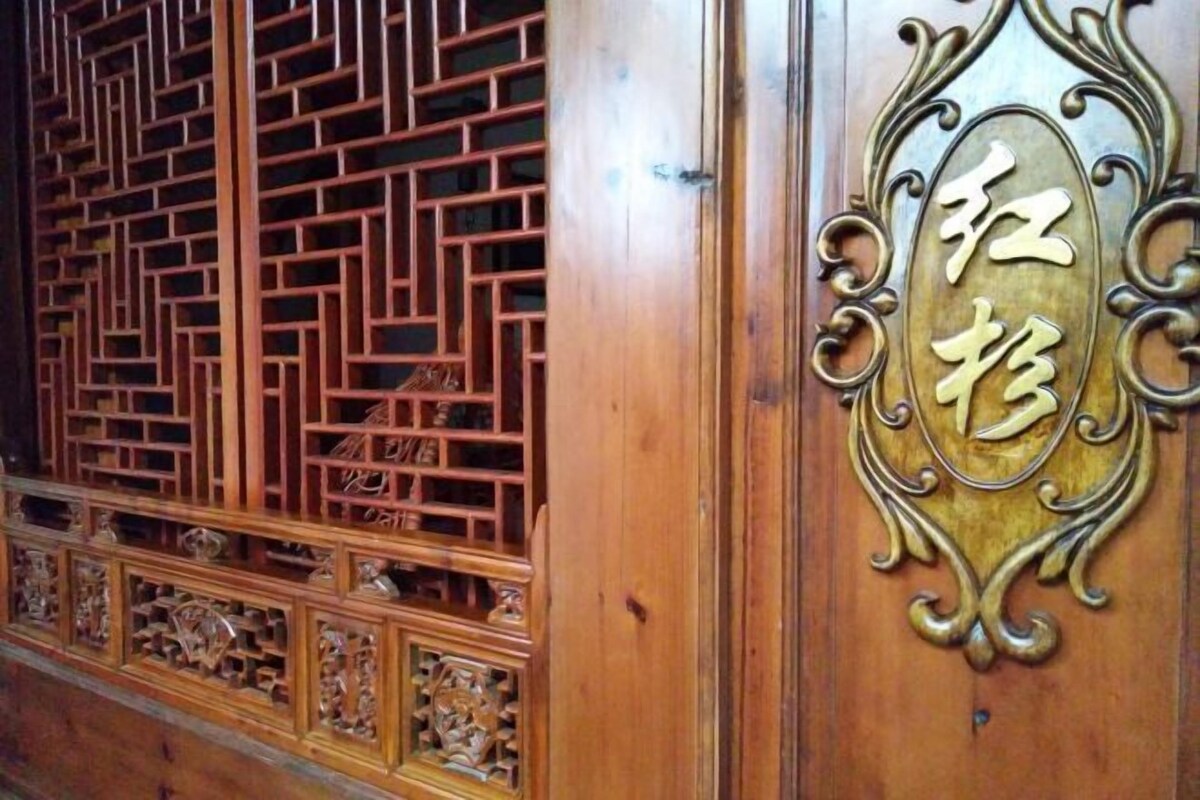 A wooden door with intricate lattice design and a decorative plaque with Chinese characters.