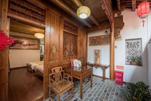 Ein traditionell eingerichtetes Zimmer mit Bett, Holzmöbeln, einem Tisch und Dekorationselementen.