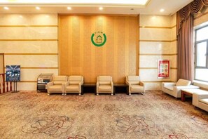 A hotel lobby with a reception desk, seating area, and a patterned carpet.