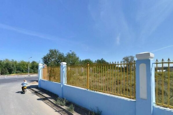 A paved road with a blue wall and yellow fence on one side.