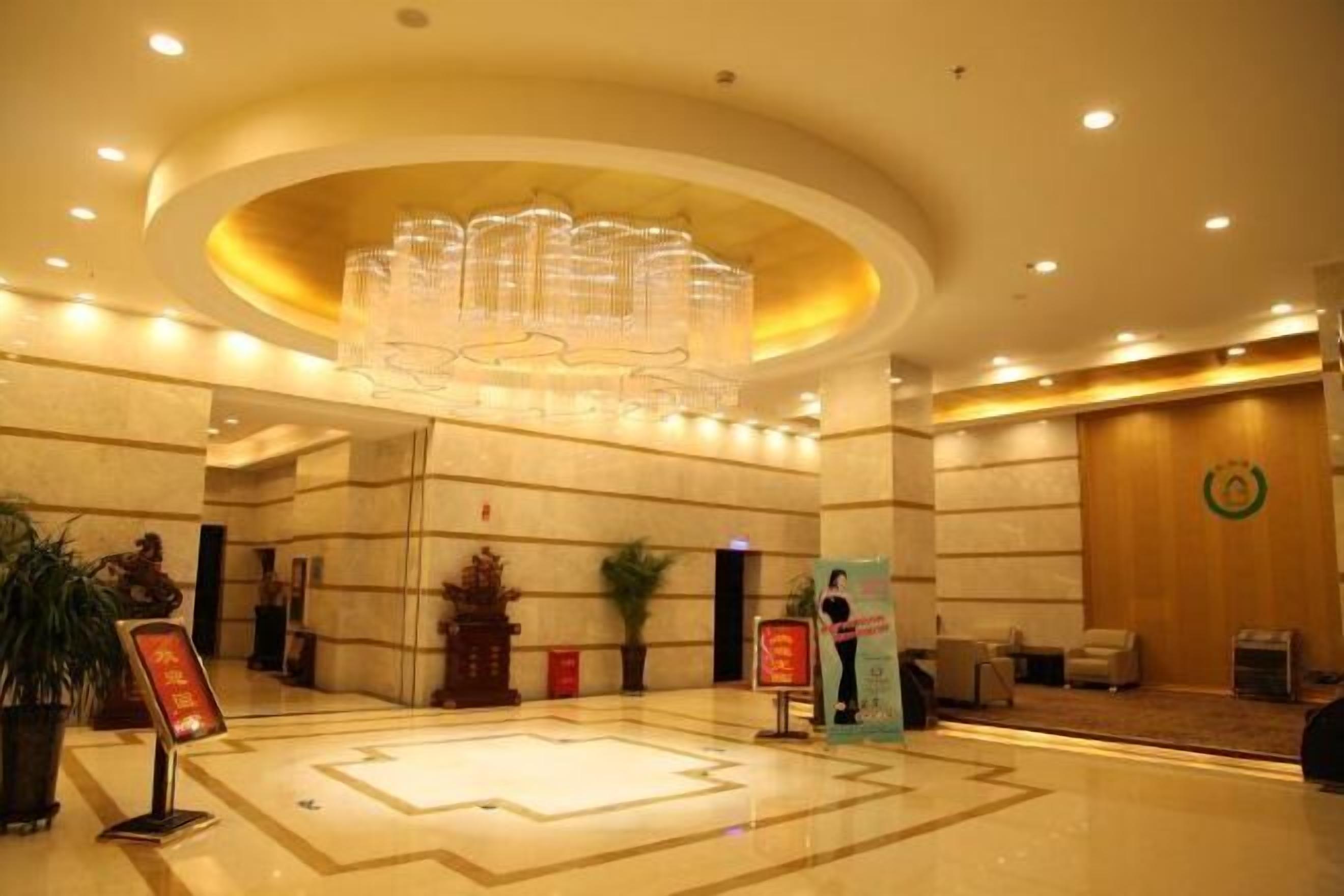 A hotel lobby with a large chandelier, marble flooring, and a reception desk.