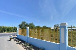 A paved road with a blue wall and yellow fence on one side.