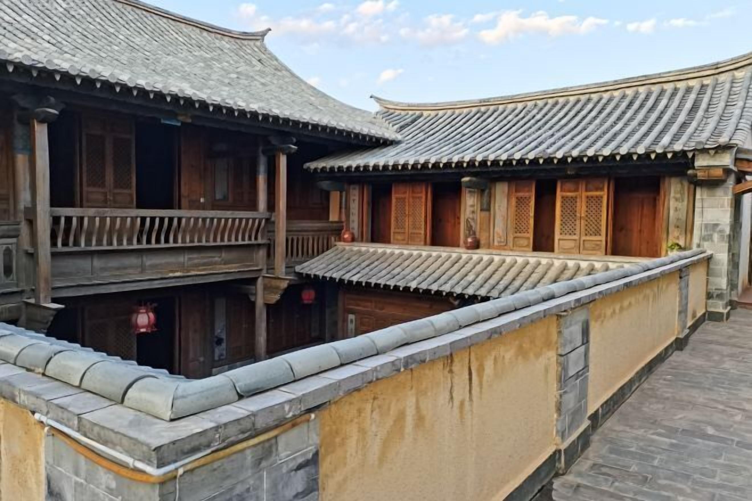 A traditional courtyard with wooden buildings, tiled roofs, and stone walls.