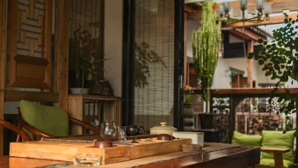 A traditional Japanese-style room with tatami flooring, a low wooden table with tea set, and a sliding door leading to a garden.