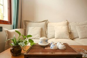 A cozy living room with a sofa, a wooden coffee table with teapots, cups, and a plant. - Mulanci Inn (Jianshui)