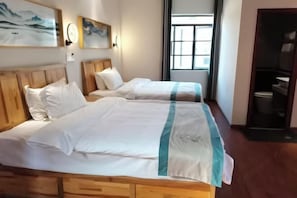 A hotel room with two beds, wooden headboards, and artwork on the walls.