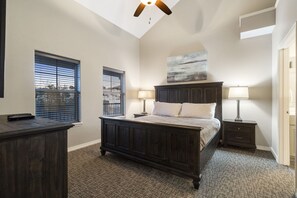 Cozy retreat with a dark bed, nightstands, and a ceiling fan, offering a peaceful atmosphere.
