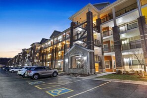 Hotel features a modern design with a combination of brick and stone facades, multiple balconies, and a central entrance with a stone archway.
