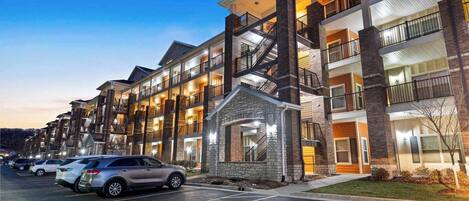 A multi-story hotel with a central entrance, parking lot, and a clear handicap parking space.