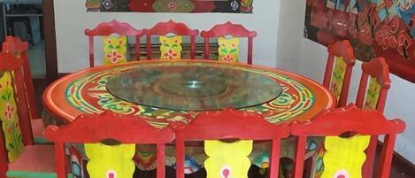 Uma mesa redonda com tampo de vidro, rodeada por cadeiras com desenhos florais.