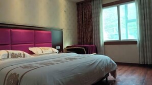A hotel room with a large bed, a headboard, a window with curtains, and a wooden floor. - Reshuitang Hotel (Li County)